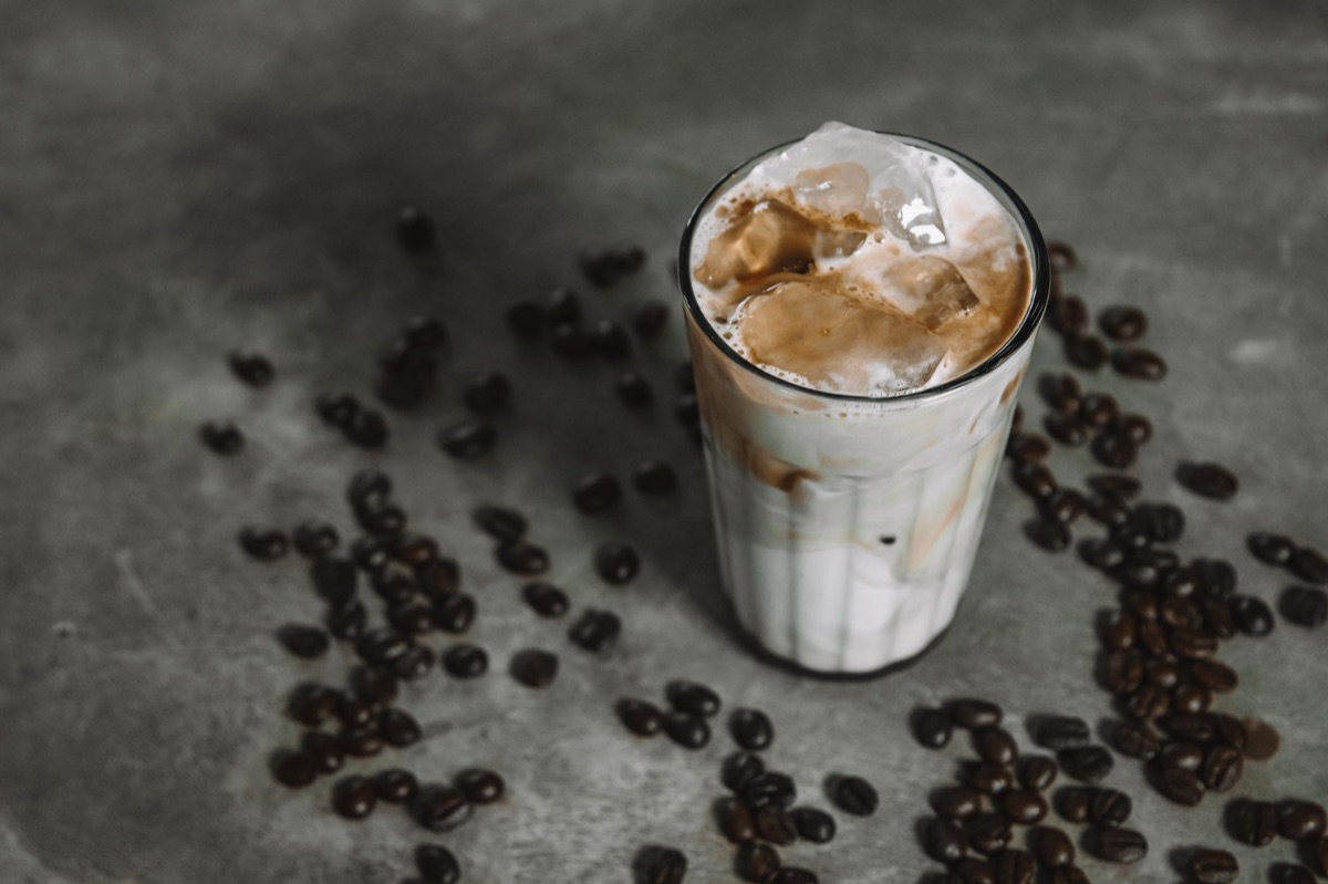 Un bicchiere di caffè freddo con cubetti di ghiaccio e un tocco di latte